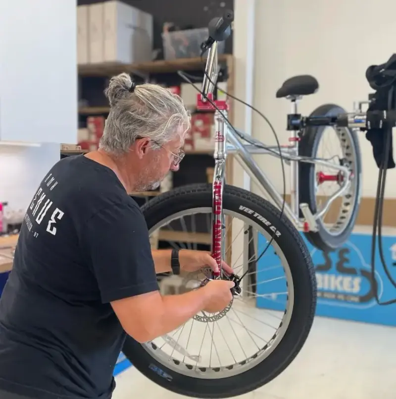 Technicien réglant la roue avant d’un vélo dans l’atelier Avenue du Vélo