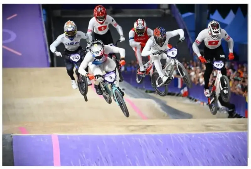Pilote de BMX race lancé sur une piste de compétition